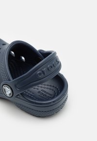 Mörkblå Crocs-klack med ventilationshål, justerbar hälen och texturerad vadderad fotbädd på vit bakgrund.