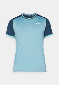 Camiseta deportiva de color azul claro con paneles de hombro en azul marino, cuello redondo y mangas cortas. Presenta un pequeño logo blanco en el pecho.