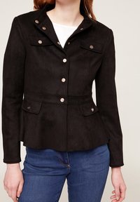 Svart mockajacka med figurnära design, guldfärgade knappar, krage och två framfickor med lock.