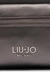Metallic grå lædertaske med en struktureret overflade, der har en sølvfarvet lynlås og prægede branding "LIU·JO MILANO" på fronten.
