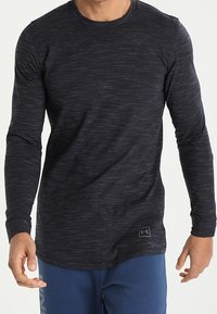 Långärmad mörkgrå T-shirt med en strukturerad, melerad mönster. Har rund hals och Under Armour-logotyp på fållen.