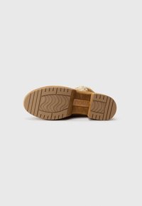 Sola di un boot in suede marrone con suola in gomma tan testurizzata e logo "mou" impressa nella zona dell'arco.