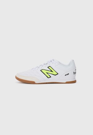 White athletic shoe with neon yellow and black accents, textured leather upper, gum rubber sole, and light cushioning for comfort.