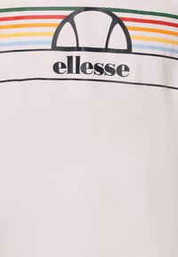 White t-shirt featuring "ellesse" logo in black. Above the logo are horizontal stripes in green, red, yellow, and blue. Soft material, casual design.