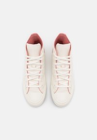 Vysoké boty z krémové plátna s růžovými akcenty. Mají bílé tkaničky a texturovanou podrážku. Interiér je podšitý měkkou růžovou tkaninou.