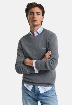 Grå tekstureret sweater med rund hals, over en lyseblå og hvid stribet skjorte med knapper. Justerbare manchetter. Afslappet pasform.
