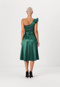 Robe en satin vert à une épaule avec accent froncé, corsage ajusté et jupe évasée. Dispose d'une fermeture éclair au dos et d'une texture lisse.