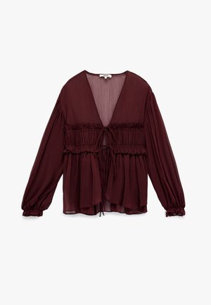 Blusa transparente de color burdeos oscuro con mangas largas abullonadas, detalles de volantes fruncidos y cierres de lazo en la parte delantera, exhibida sobre un fondo blanco.