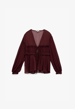 Blusa transparente de color burdeos oscuro con mangas largas abullonadas, detalles de volantes fruncidos y cierres de lazo en la parte delantera, exhibida sobre un fondo blanco.