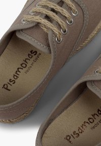 Bruine canvas espadrilles met geweven juten accenten en metalen oogjes. De binnenkant heeft een geperst merk "Pisamonas, Hecho en España."
