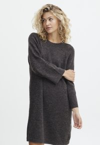 Strikket sweaterkjole i mørkegrå, med rund halsudskæring, lange ærmer og en afslappet pasform. Materialet virker blødt og struktureret.