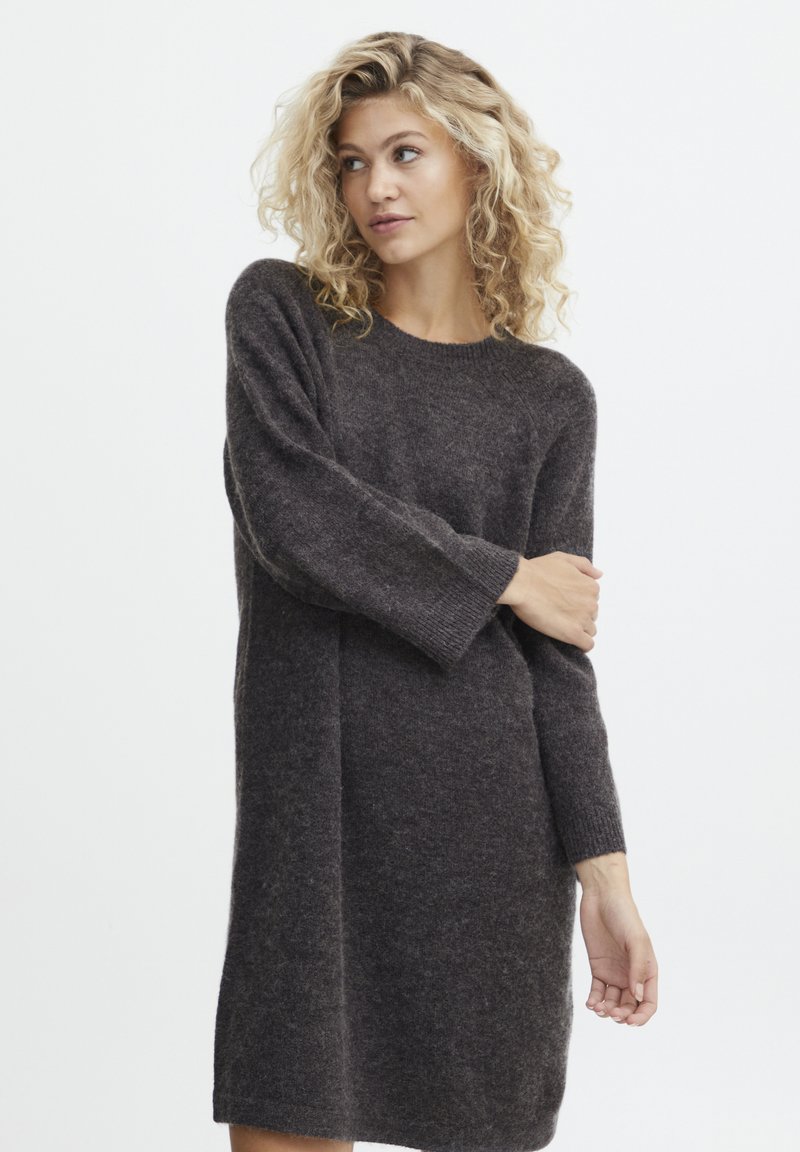 Strikket sweaterkjole i mørkegrå, med rund halsudskæring, lange ærmer og en afslappet pasform. Materialet virker blødt og struktureret.