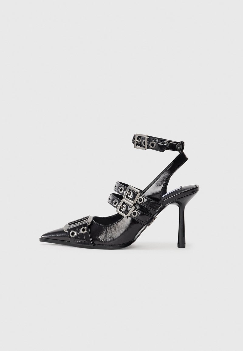 Shoe de salto alto preto com bico fino em couro patente brilhante, design com tiras apresentando fivelas de metal e ilhós, e um salto fino stiletto.
