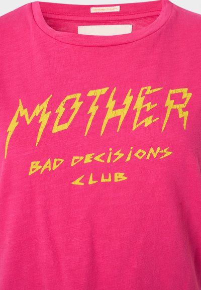 Fuksijos spalvos medvilninė marškinė su geltonu, nusidėvėjusiu tekstu, skaitančiu "MOTHER BAD DECISIONS CLUB" ryškiu, kampuotu šriftu. Trumpomis rankovėmis.