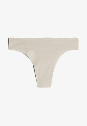 Beige bezšvové tanga vyrobené z měkkého materiálu, s minimalistickým designem, vysokými boky a hladkým povrchem.