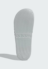 Bílá gumová podrážka boty se zigzagovým vzorem a vyrytou značkou "adidas". Hladký povrch s zaoblenými okraji.