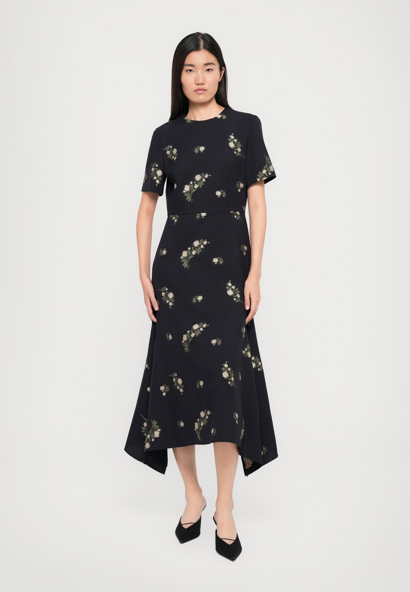 Robe marine à motifs floraux, à manches courtes et à ourlet asymétrique. Le tissu semble lisse, avec des accents floraux de couleur claire.