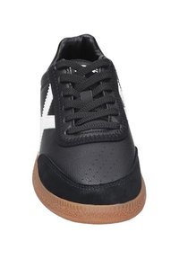 Sneaker nera con tomaia in pelle, accenti laterali bianchi e suola in gomma testurizzata. Presenta lacci rotondi e fori sulla punta.