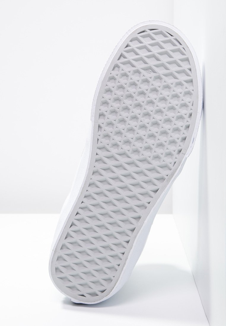 Zapatilla blanca con una suela de goma texturizada que presenta un patrón de diamantes, lados lisos y un diseño minimalista.