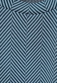 Tyg i fiskbensmönster med växlande ljusblå och marinblå ränder. Slät textur med symmetriska designelement.