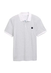 Polo shirt blanc avec motif géométrique bleu marine, texture tricotée et col blanc uni. Présente un petit logo bleu marine sur la poitrine gauche.
