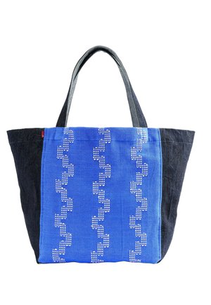 Borsa a tracolla con lati e manici neri, pannello frontale blu con tre file verticali di motivi geometrici bianchi ricamati.