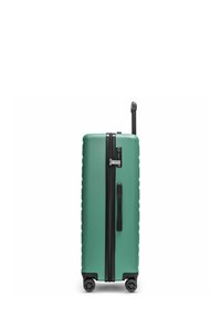 Maleta rígida en verde menta con acentos negros, que cuenta con un zipper vertical, asa telescópica y cuatro ruedas giratorias para mayor movilidad.