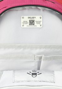 Intérieur de valise en tissu rose avec doublure grise, doté d'une plaque d'information en métal et de plusieurs poches pour l'organisation. Code QR inclus.