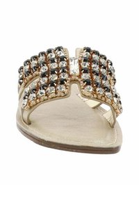 Sandalo piatto con base dorata, caratterizzato da una ampia striscia decorativa adornata con strass neri e trasparenti disposti in un motivo a griglia.