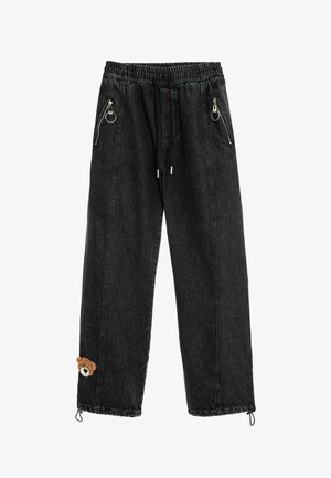 Pantalones vaqueros negros con cinturilla elástica, cordón, bolsillos con cremallera, bajos ajustables y un pequeño parche de osito cerca del tobillo izquierdo.