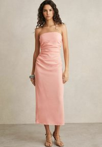 Strapless, figurnära midiklänning i mjuk rosa satin med samlade detaljer på sidorna och en slät, glansig yta.