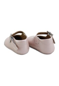 Zapatos de charol rosa claro con punta redonda, tira de tobillo y acento de lazo decorativo, que presentan una textura suave y una suela flexible.