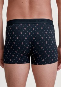 Navy boxer briefs with a geometric pattern in red and cream. Made of soft fabric, featuring a black waistband with the brand name embossed.