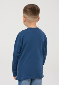 Granatowa koszulka z długim rękawem z bawełny, z okrągłym dekoltem i luźnym krojem. Widok z tyłu pokazuje gładką teksturę i prosty design.