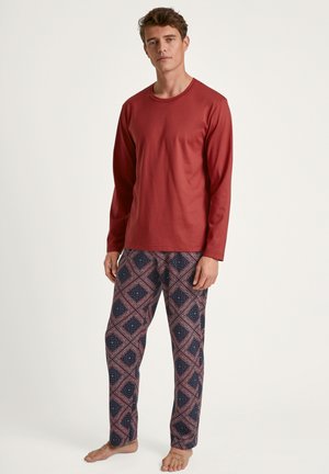 Chemise rouge à manches longues associée à un pantalon bleu marine à motifs avec un design en losanges blancs et rouges. Coupe décontractée, tissu doux.