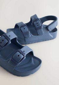 Sandale albastre din plastic cu două curele reglabile cu catarame albastre închise, partea superioară texturată și o talpă profilată cu talpă aderentă.