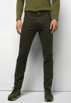 Olijfgroene corduroybroek met een slim fit, voorzien van voorzakken en een knoopsluiting, gecombineerd met donkergroene veterschoenen.
