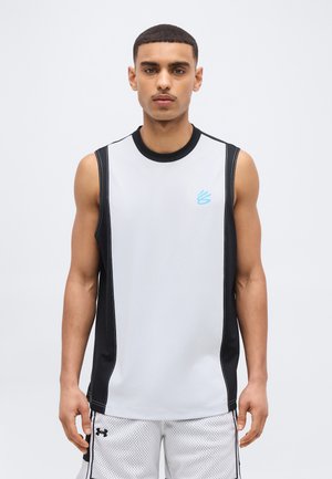 Young man wearing sleeveless black and white athletic top and white mesh shorts, standing against plain light background.