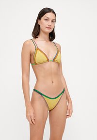 Gul bikini i trekantdesign med flerfargede detaljer. Har tynne stropper og intrikate detaljer langs kantene. Teksturert stoff.