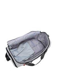 Sac de sport gris avec un compartiment principal spacieux, tissu lisse, une petite pochette grise à l'intérieur et des accents de fermeture éclair noirs.