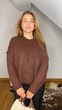 Rudas megztinis su reljefiniu tekstūru, apvaliu kaklu ir nukritusiais pečiais. Su juodomis kelnėmis ir grietinėlės spalvos rankine su rudomis detalėmis.
