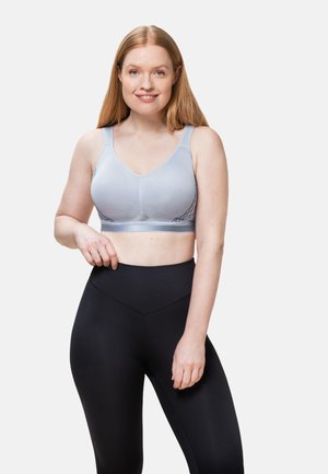 Lichtblauwe sportbeha van een textuurstof, met brede bandjes en een V-halsontwerp, gecombineerd met hoge zwarte leggings.