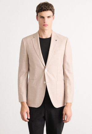 Light beige blazer with a checkered pattern, single button closure, two front pockets, and a notch lapel; paired with a black T-shirt.