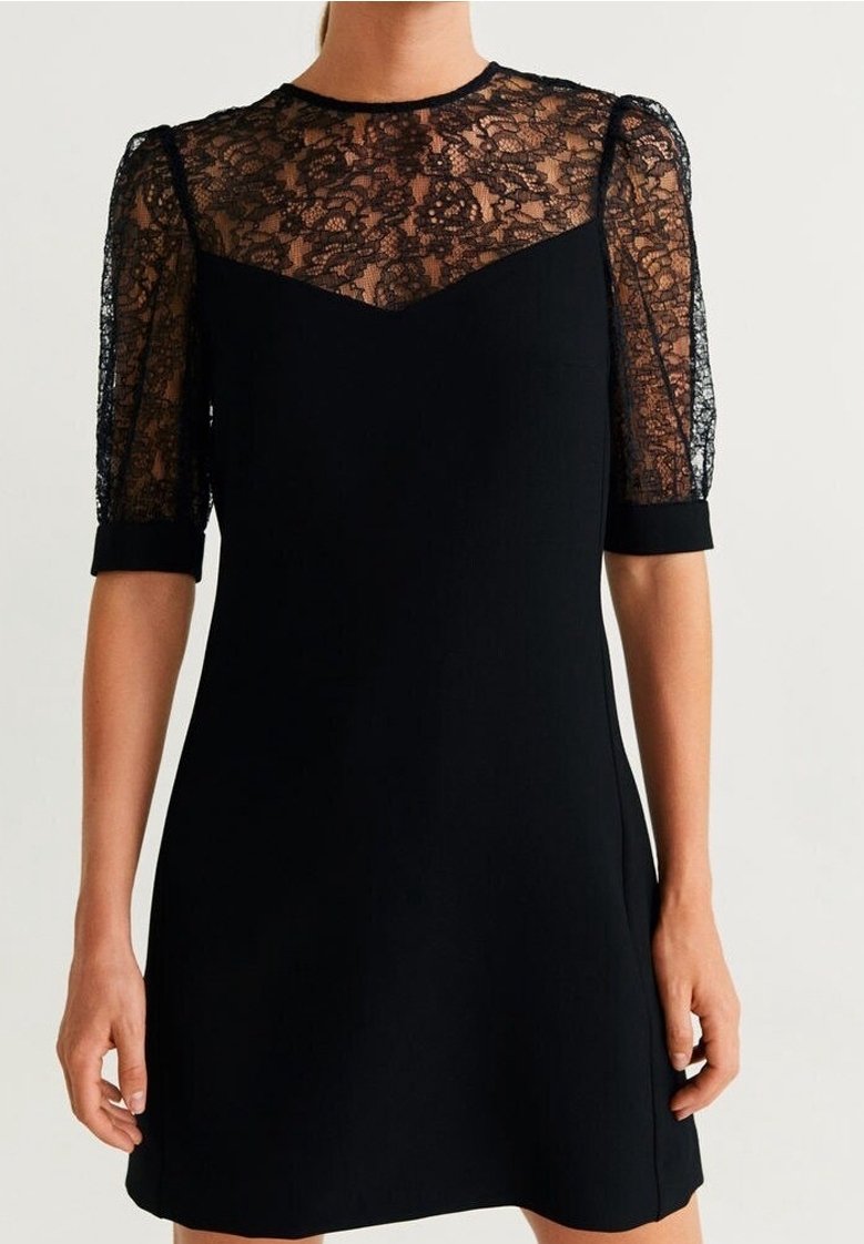 Schwarzes Kleid mit einem durchsichtigen Spitzentop und kurzen Ärmeln. Das Oberteil ist glatt, während der Rock eine ausgestellte Silhouette hat.