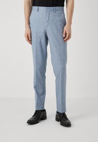 Lichtblauwe op maat gemaakte broeken van een gestructureerde stof, met een slim fit, zijzakken en een gladde tailleband, gedragen met zwarte dress schoenen.