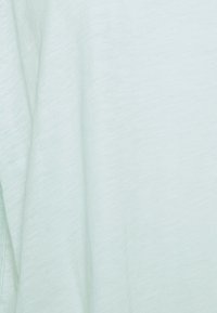 Ljus mintgrön tyg med en mjuk, något texturerad yta. Materialet är glatt och faller mjukt, vilket ger en liten lyster.