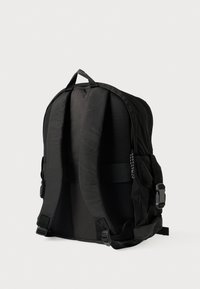 Μαύρο σακίδιο με επένδυση από δίχτυ στο ιμάντα, πολλαπλές θήκες, ρυθμιζόμενες αγκράφες και υφή με ανάγλυφο φινίρισμα.