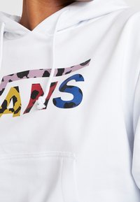 Sudadera blanca con un diseño gráfico que presenta acentos de estampado de leopardo en rosa, amarillo, rojo y azul. Incluye un bolsillo delantero y capucha con cordón.