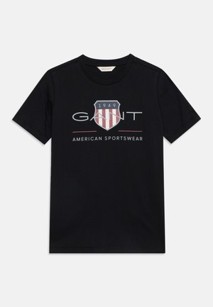 T-shirt noir à manches courtes avec col rond, avec un logo en forme de bouclier avec "1949" et texte "GANT American Sportswear" à l'avant.