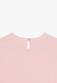 Roze polo met korte mouwen, voorzien van een opening op de rug met een kleine knoop. Zachte stof met een gladde textuur. Minimalistisch ontwerp.
